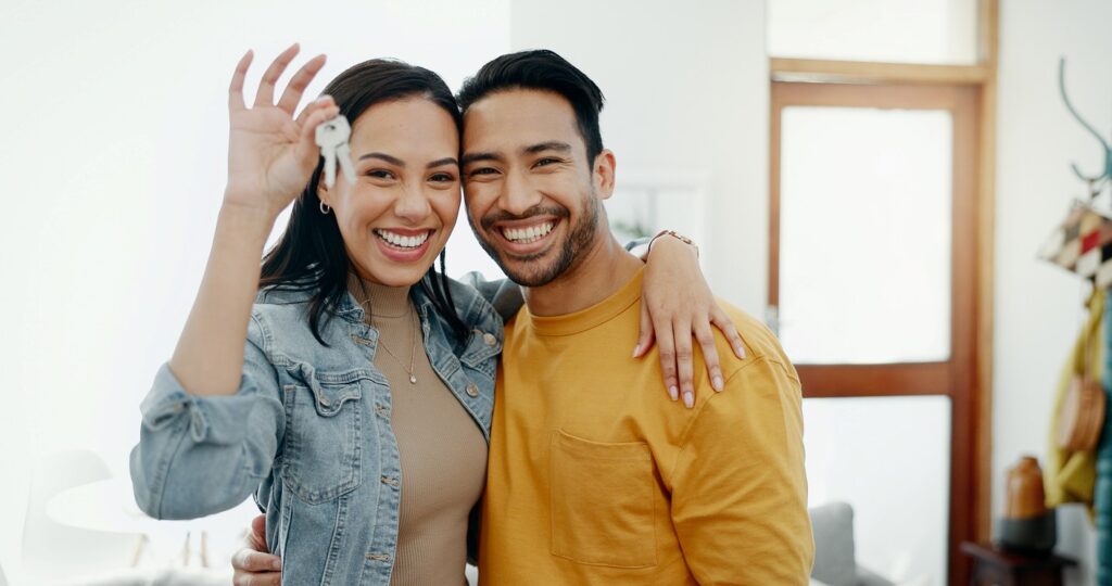 A man and woman excitedly hold the keys to their new home.