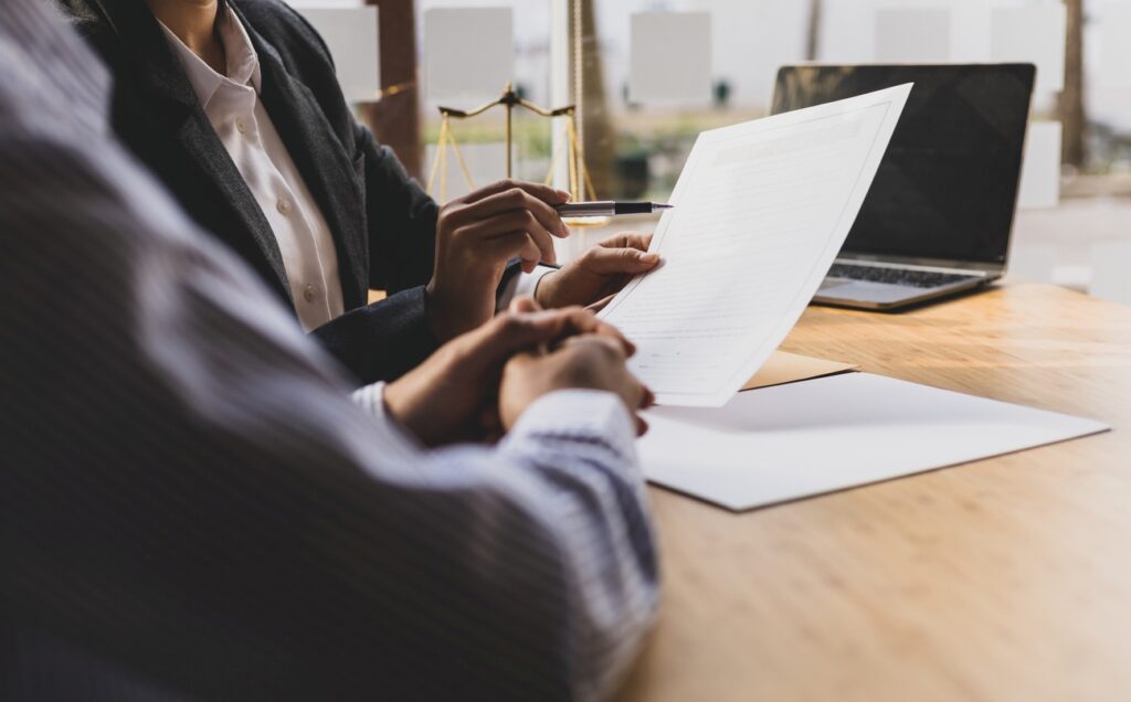 A lawyer explains the terms of the legal contract document and asks the client to sign it properly.